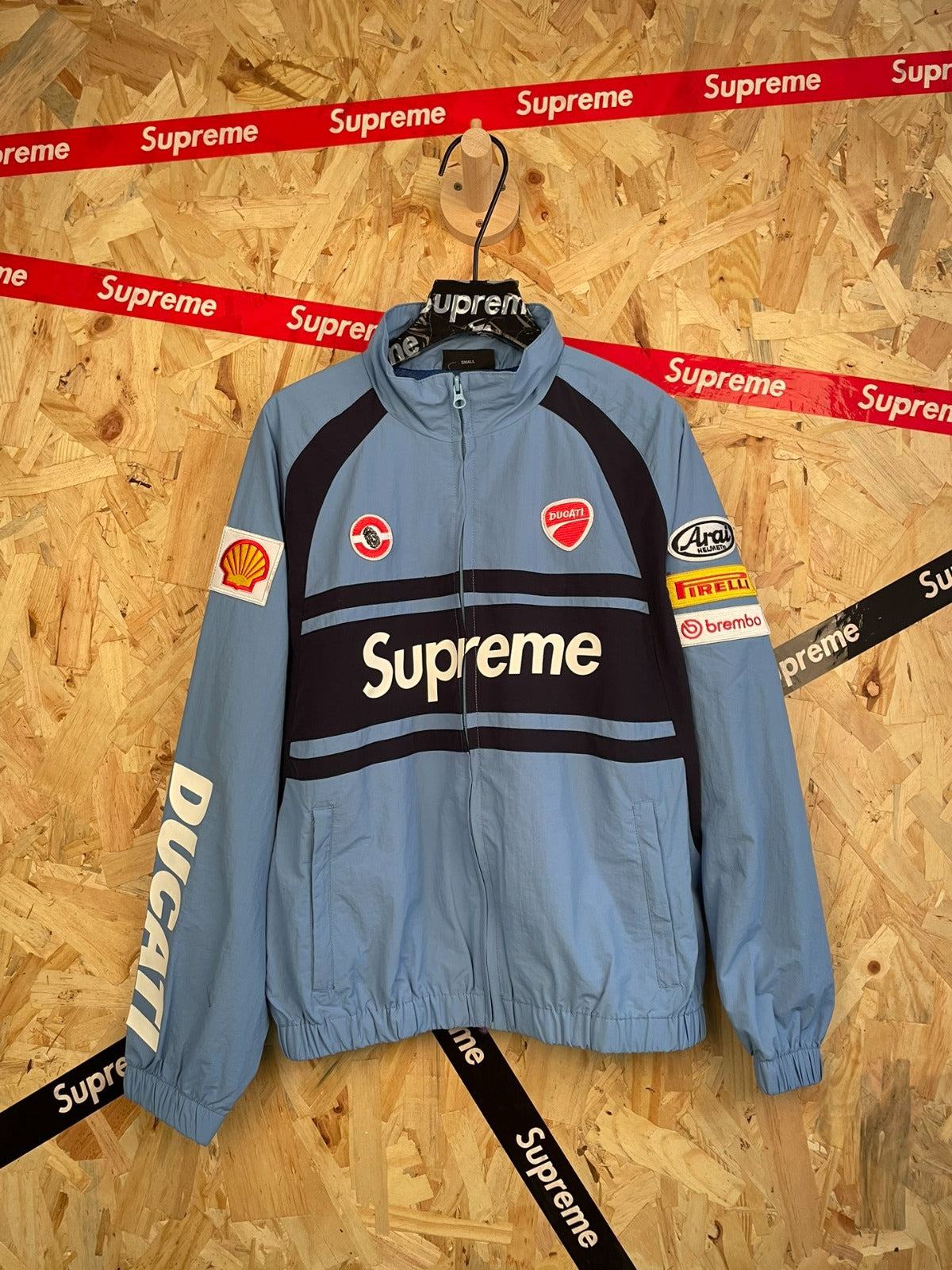 Campera azul grisácea con parches de carreras · Supreme — Supreme